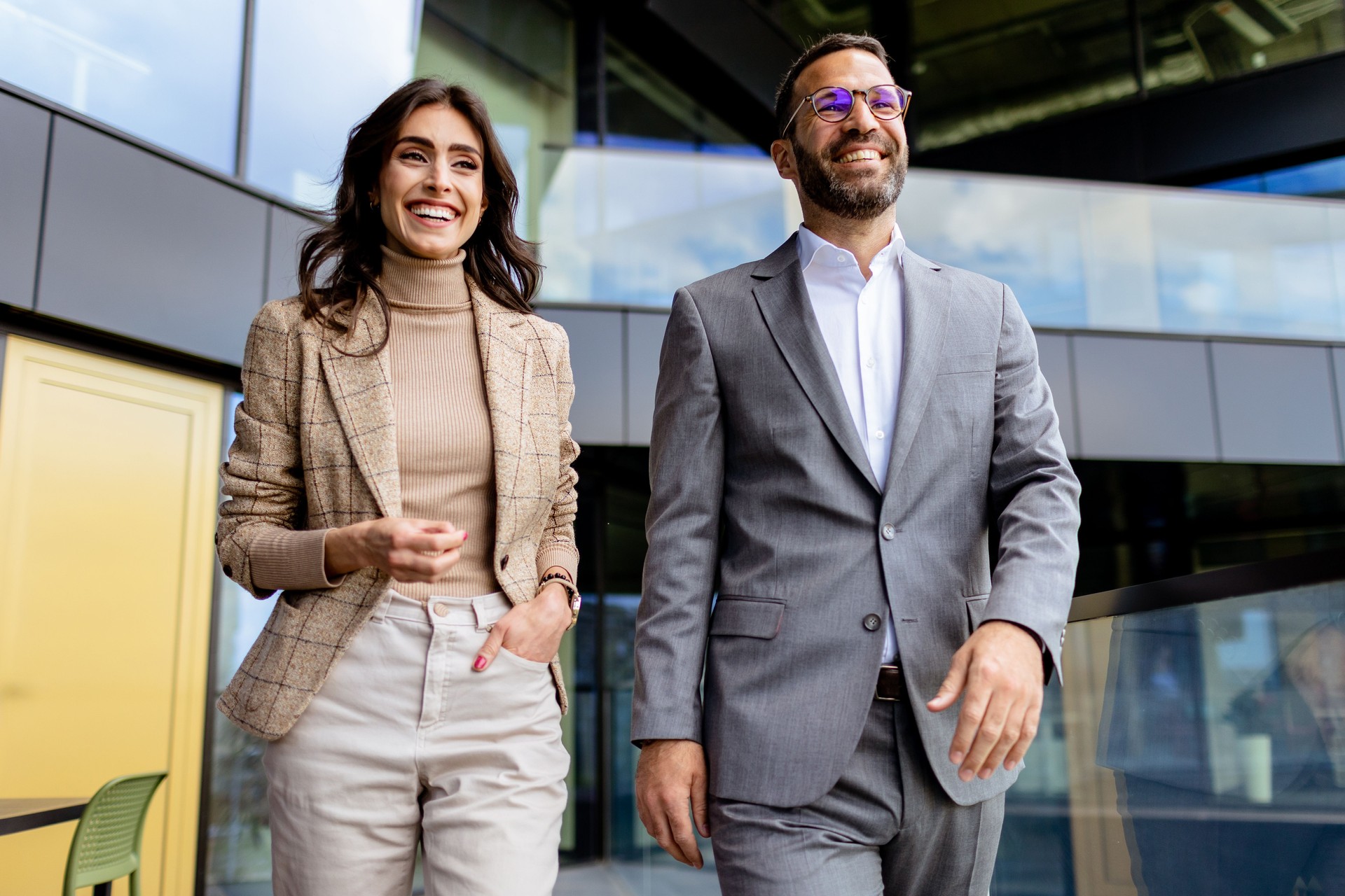 Cheerful Colleagues Exiting a Modern Office Building on a Bright Afternoon